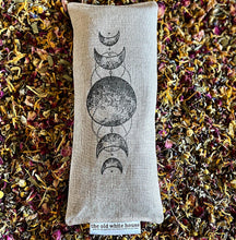 Load image into Gallery viewer, goddess eye pillow filled with a blend of rose petals, chamomile, calendula, lavender, hibiscus, and eucalyptus, and hand stamped with phases of the moon on both the eye pillow and matching bag. 
